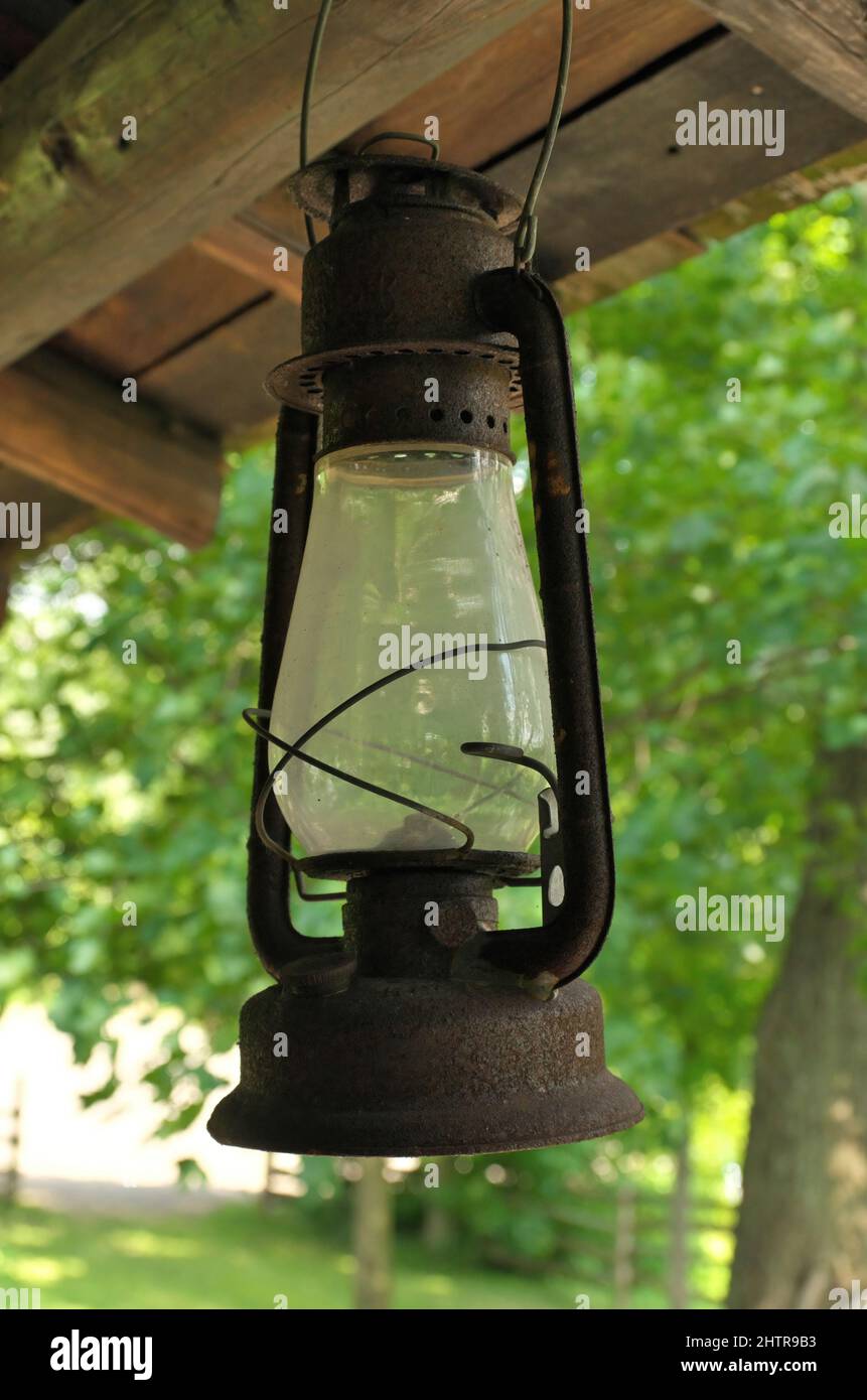 Lampada ad olio di kerosene arrugginita appesa ad un portico rustico in legno Foto Stock