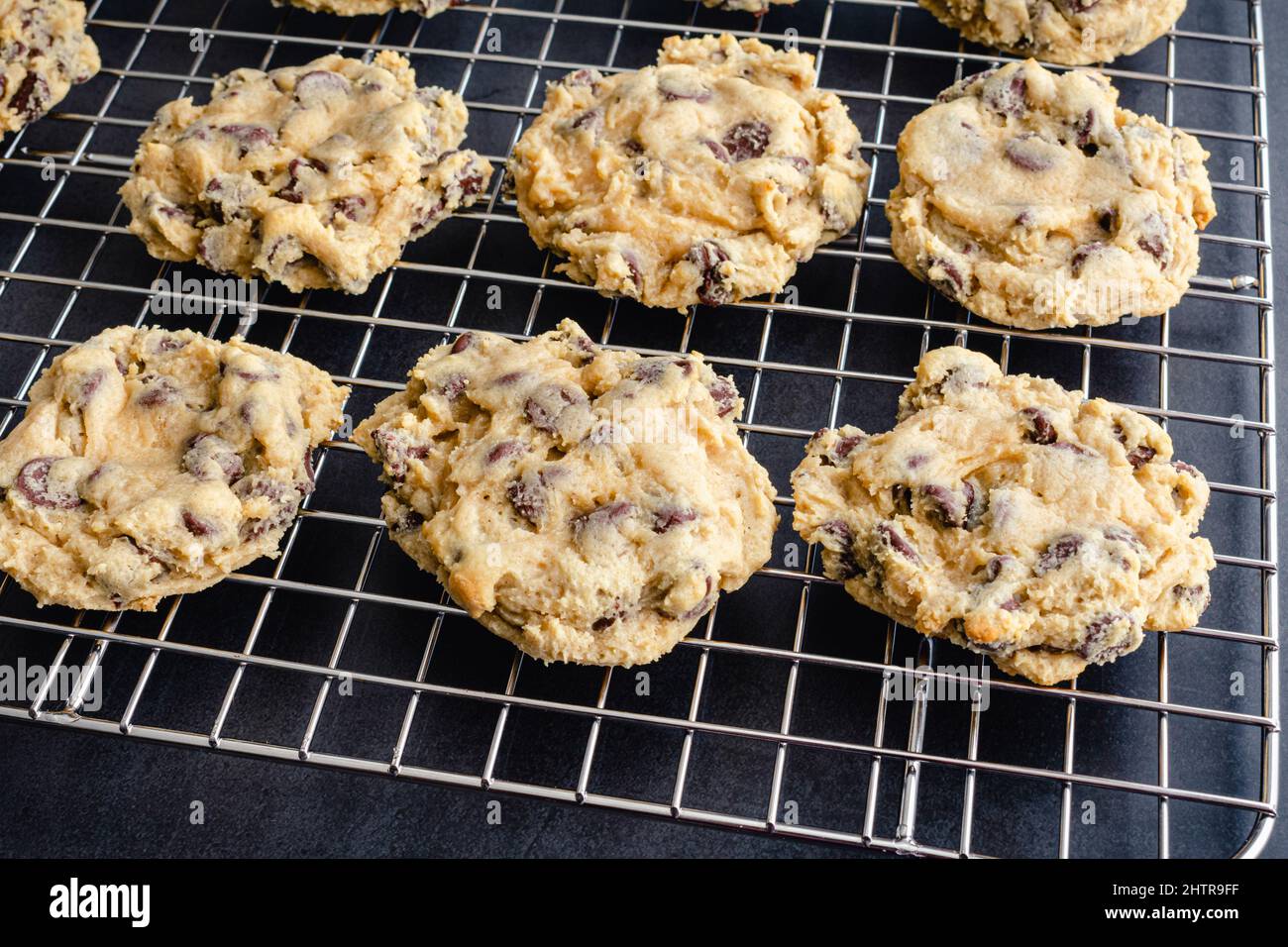 Biscotti con chip di cioccolato su una griglia di raffreddamento a filo: Biscotti con chip di cioccolato chewy appena sfornati che si raffreddano su una griglia di metallo Foto Stock