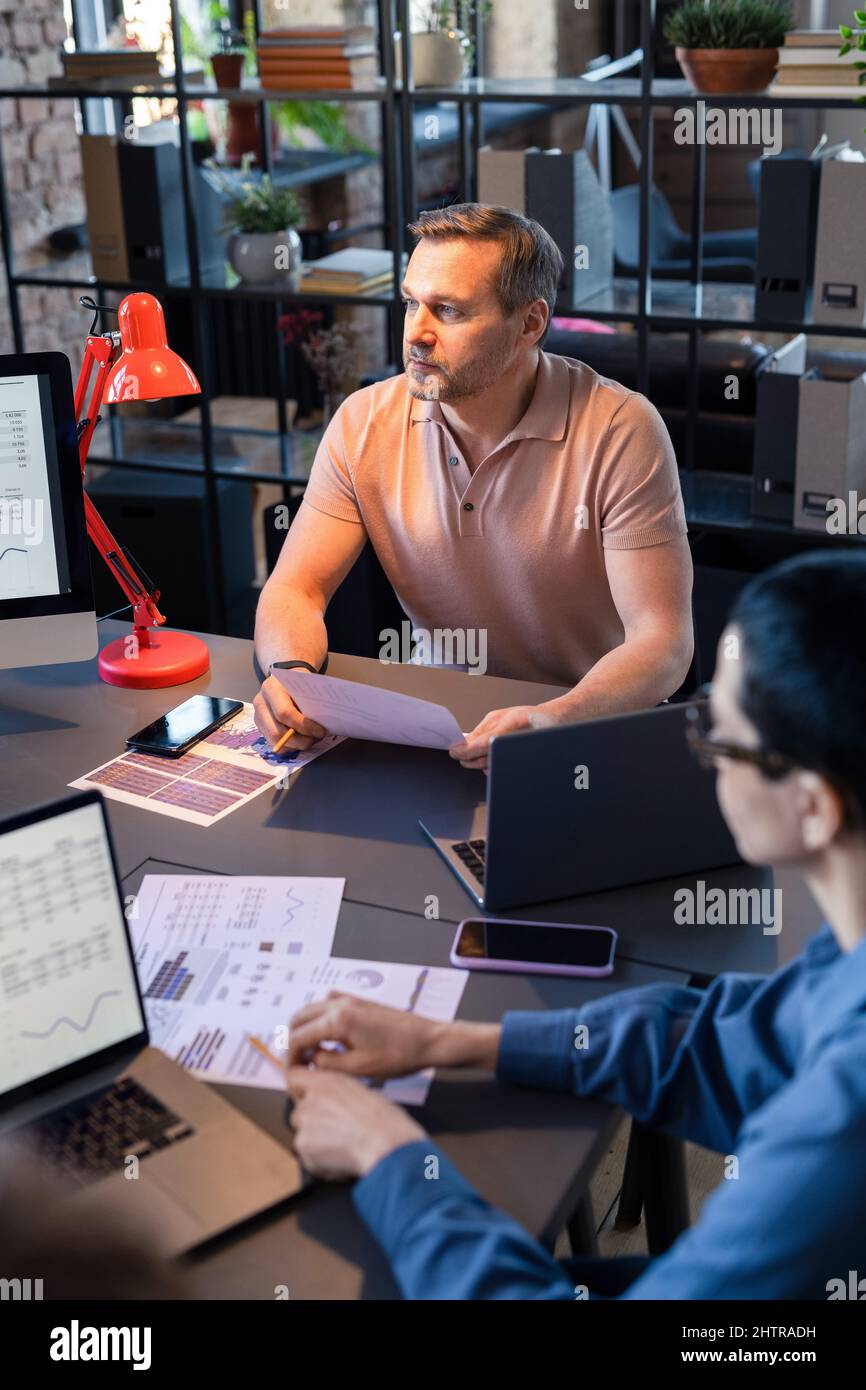 Gli uomini d'affari seduti al tavolo e che lavorano con documenti finanziari, analizzano e costruisce la strategia durante la riunione in ufficio Foto Stock