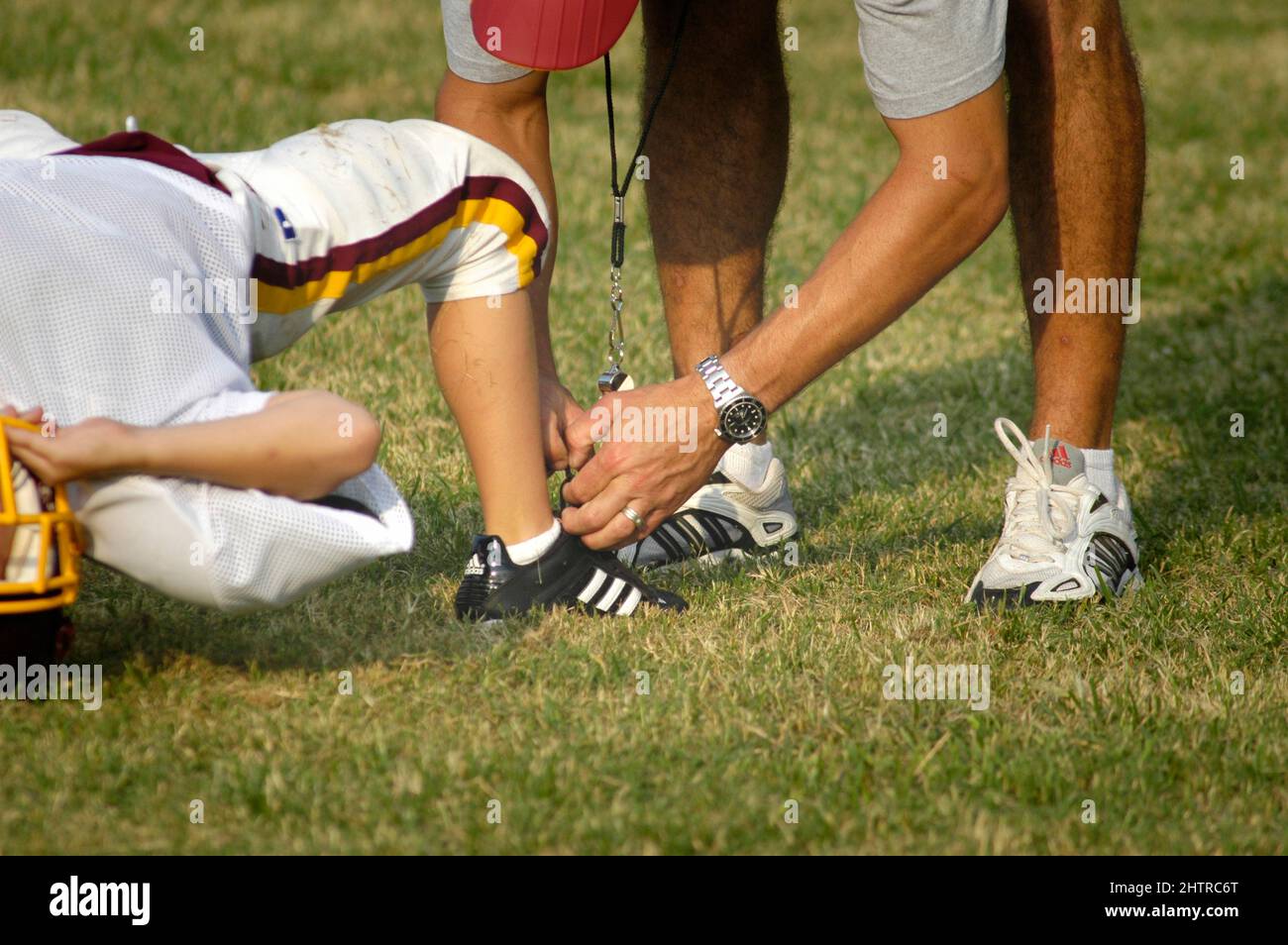 allenatore di calcio per i ragazzi in divise e pastiglie piene, ottiene  aiuto allacciando le scarpe Foto stock - Alamy