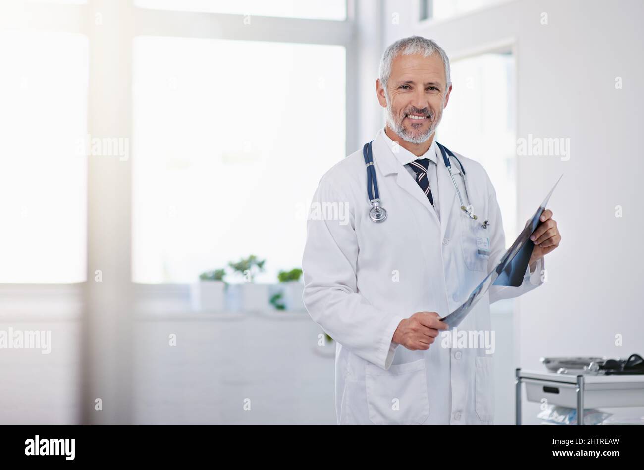 Impegno per l'eccellenza nel settore sanitario. Ritratto di un medico maturo che tiene una radiografia in un ospedale. Foto Stock