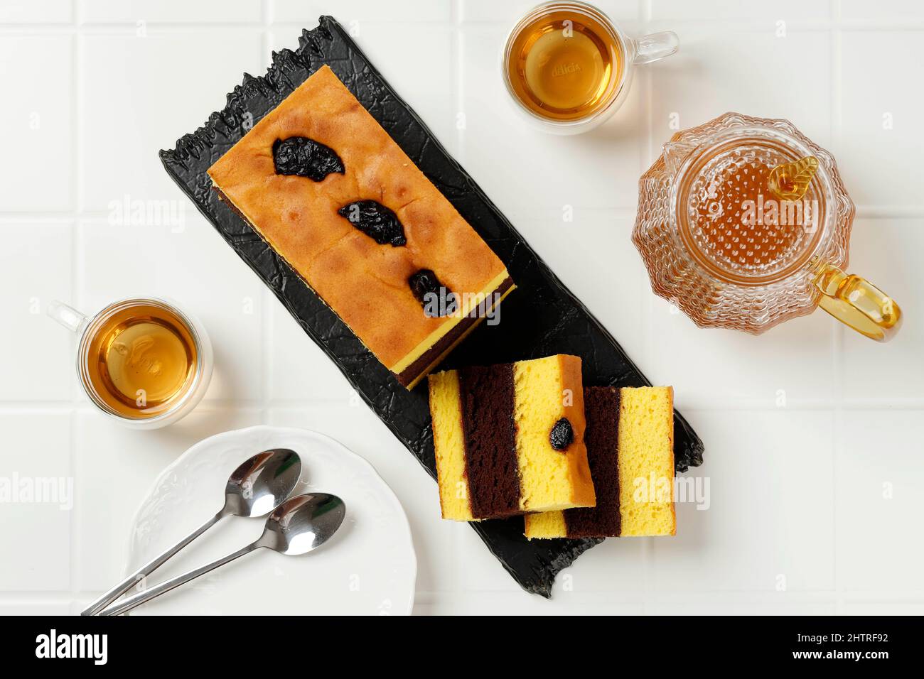 Vista dall'alto Lapis Surabaya o Surabaya Layer Cake servito con te'. Spiku è una torta in spugna di tuorlo d'uovo a tre strati con marmellata di fragole Foto Stock