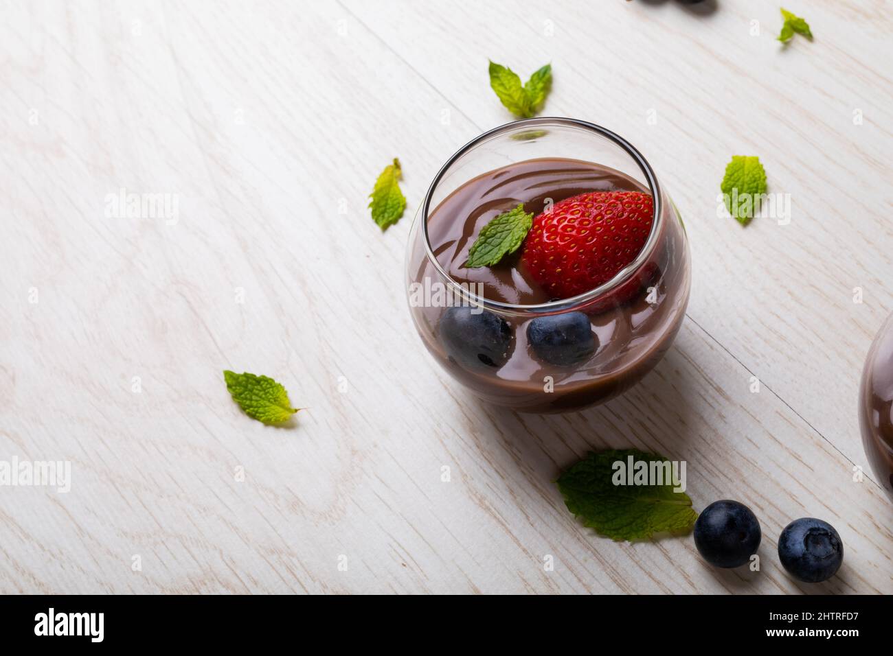 Primo piano fragola, mirtilli e foglia di menta con dessert al cioccolato servito in ciotola sul tavolo Foto Stock