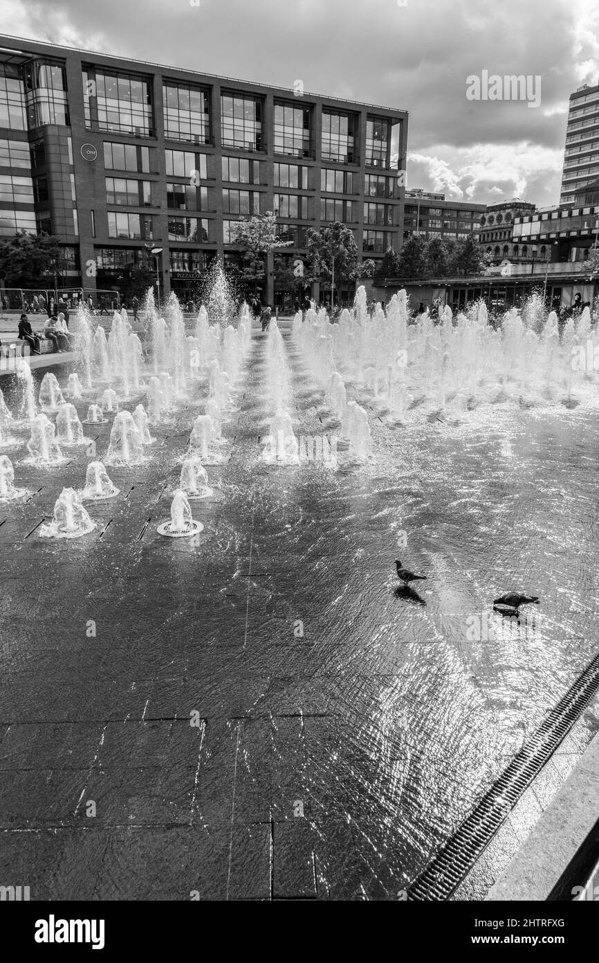 Piccadilly Gardens, Manchester, Greater Manchester, Regno Unito, fontane d'acqua del centro città con acqua potabile piccioni ed edifici sullo sfondo. Foto Stock