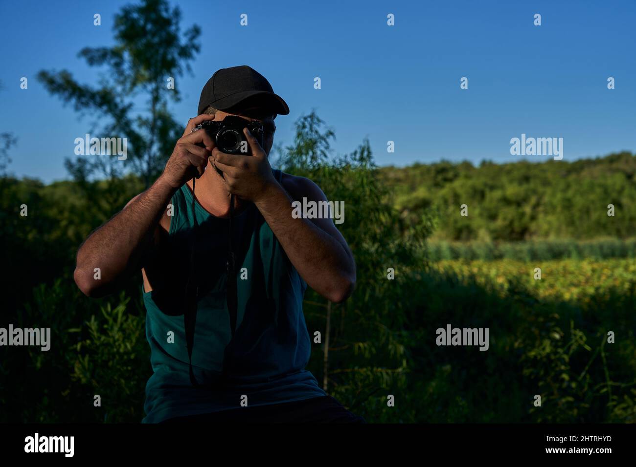 giovane che fotografa in natura con una macchina fotografica d'epoca Foto Stock