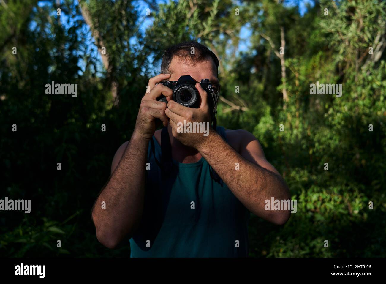 giovane che fotografa in natura con una macchina fotografica d'epoca Foto Stock