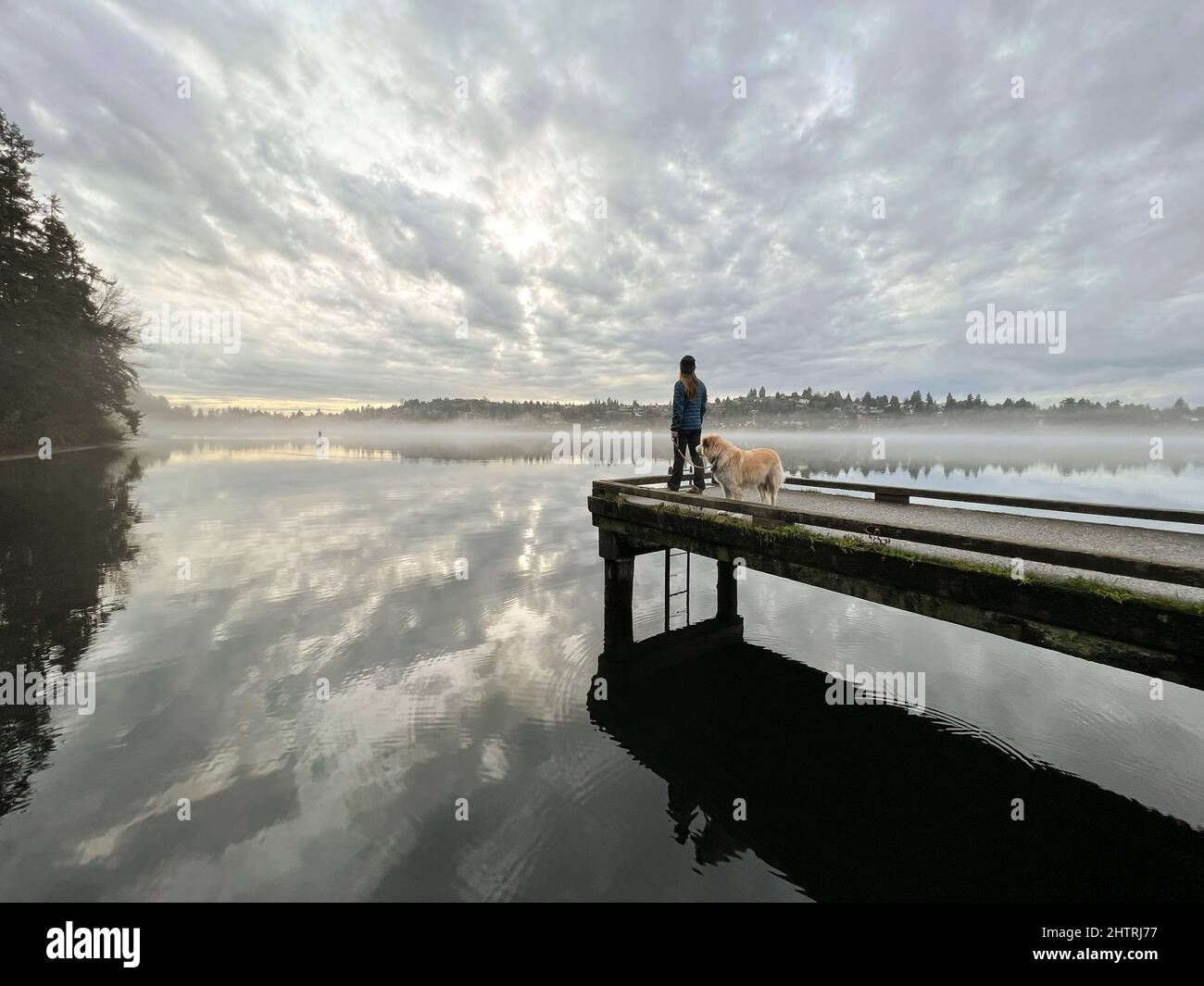 Femmina e il loro cane in piedi sul molo al Seward Park di Seattle Foto Stock