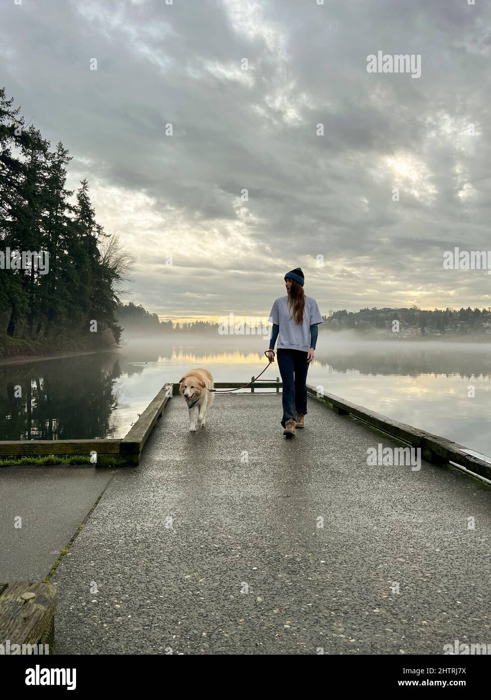 Le donne e il loro cane camminano sul molo al Seward Park di Seattle Foto Stock