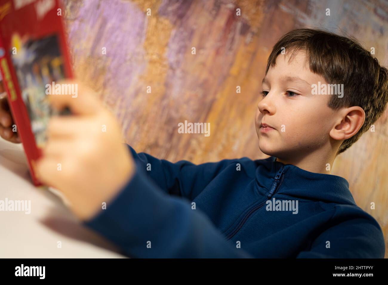 Ragazzo intelligente sta leggendo interessante libro Foto Stock