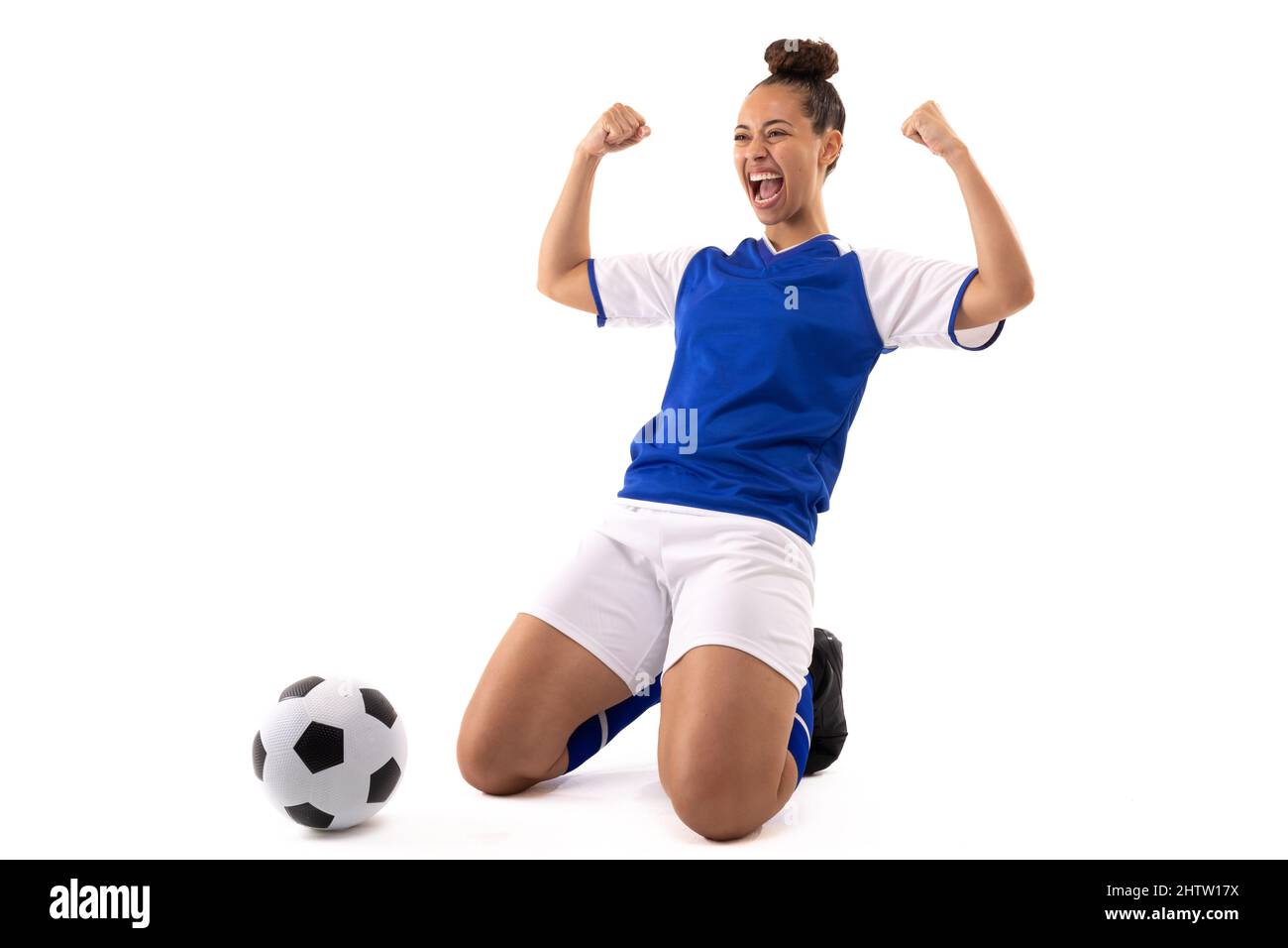 Allegro biraciale giovane donna con pugno agguato mentre inginocchiato dalla palla di calcio Foto Stock