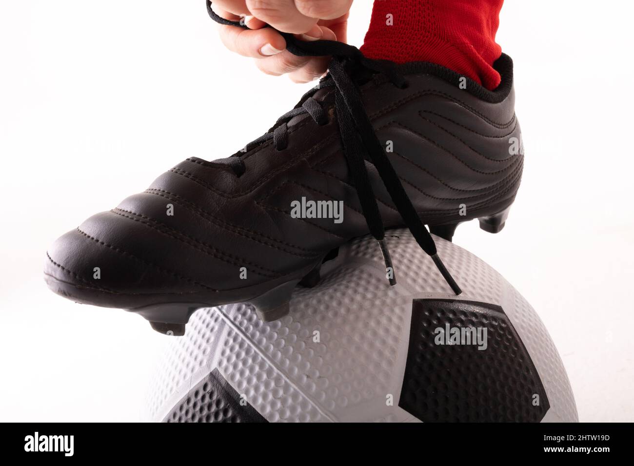 Close-up estremo di giovane donna caucasica che lega il merletto della scarpa con il piede sulla sfera di calcio Foto Stock