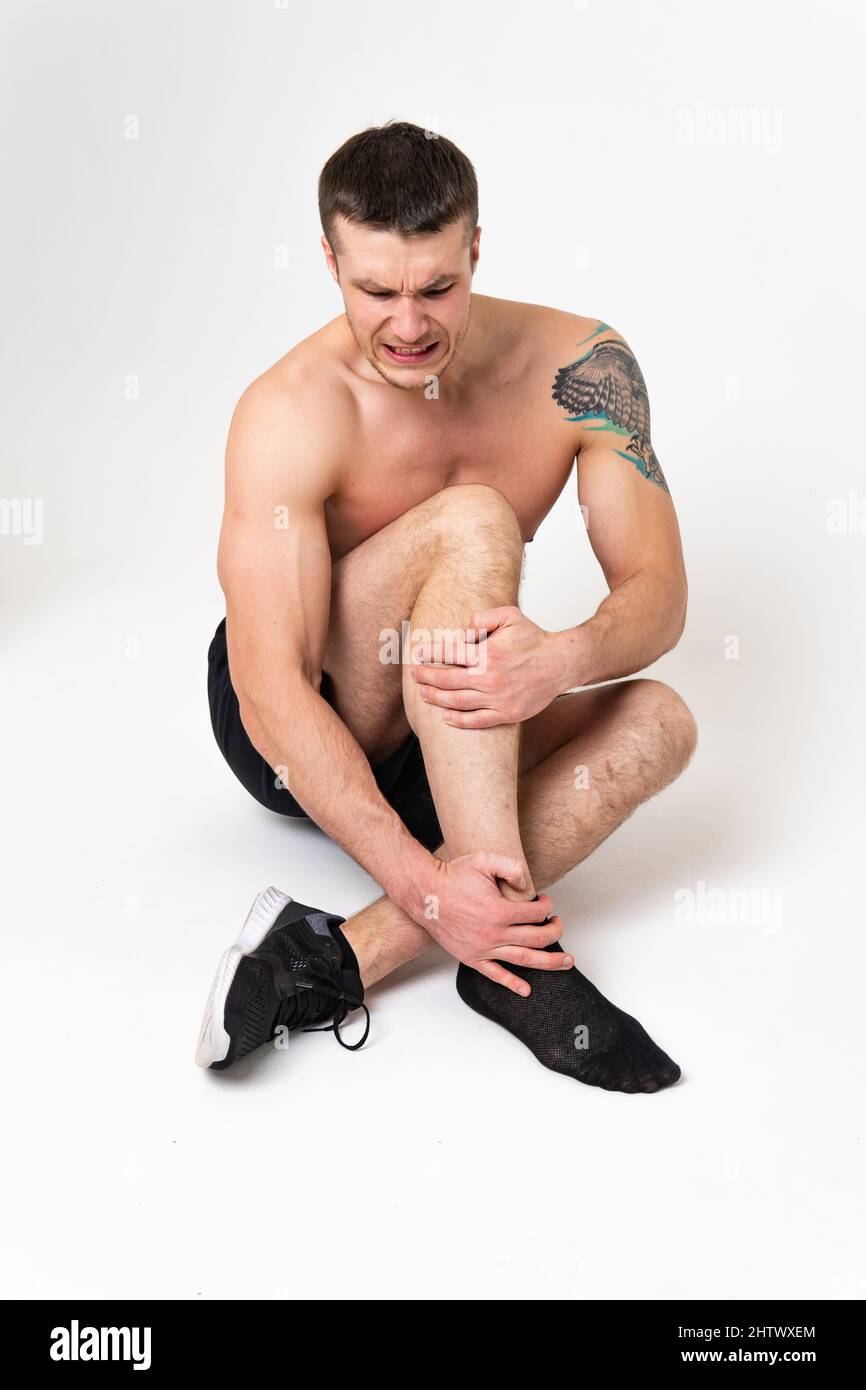 La ginocchia di un uomo danneggia su uno sfondo bianco dolore muscolare, mal di schiena caucasico stress, malattia in attesa. La tensione della parte inferiore lombare è attraente Foto Stock