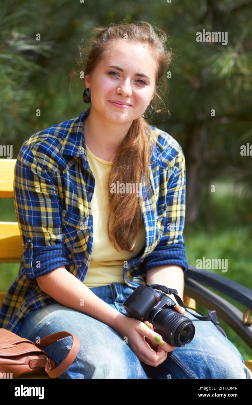 Shes più felice in una giornata di sole con la sua macchina fotografica. Una ragazza bellissima seduta in un parco con la sua macchina fotografica. Foto Stock