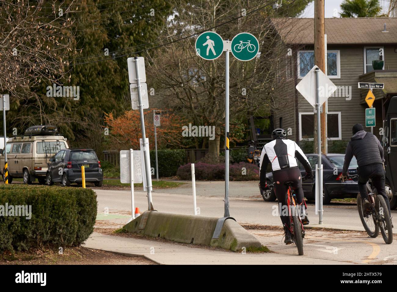 I ciclisti che cavalcano le loro biciclette su un percorso condiviso per biciclette e una passerella pedonale, Vancouver, BC, Canada Foto Stock