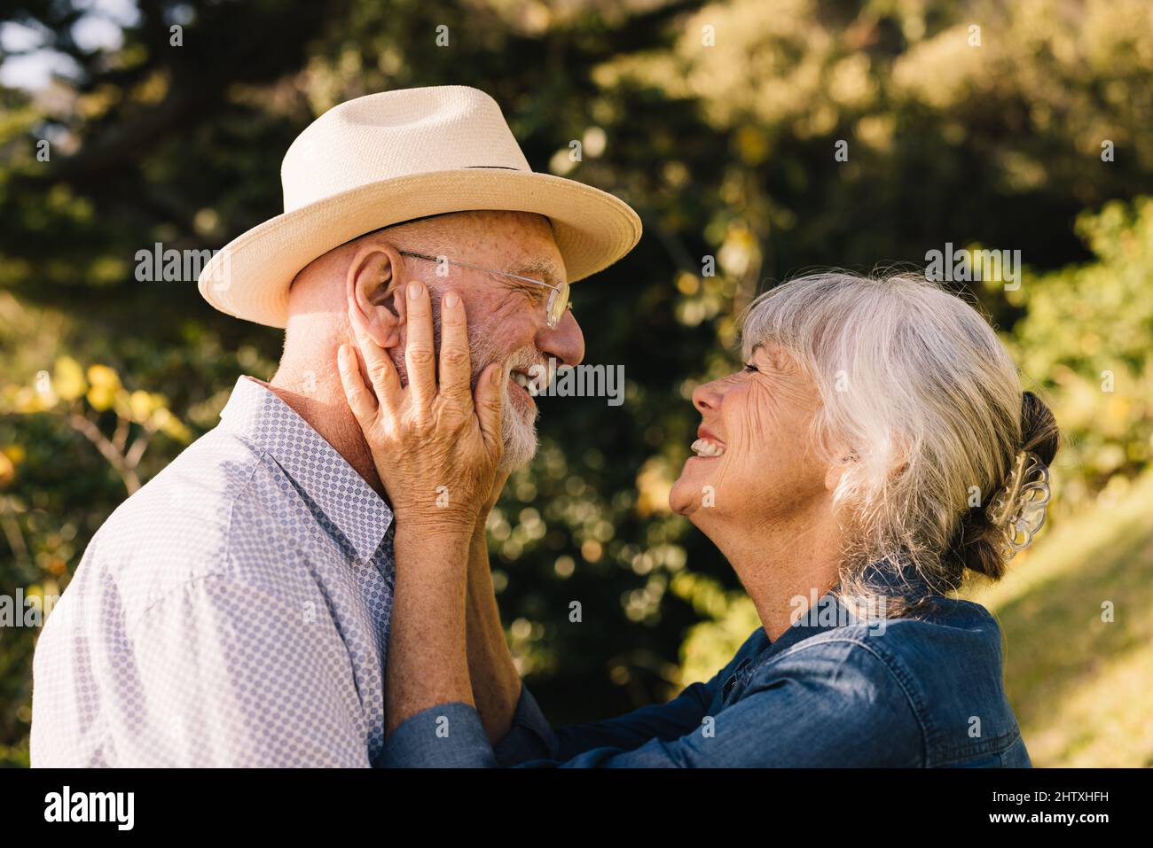 Coppia anziana allegra sorridente l'un l'altro con amore e affetto. Coppia dai capelli grigi che condivide un momento romantico mentre si trova in un parco. Buon eld Foto Stock