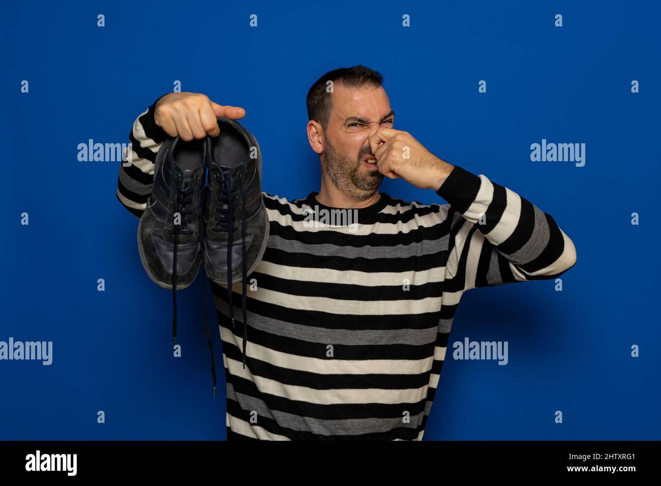 Un uomo tiene le sneakers nelle sue mani. Odore sgradevole. Gambe puzzolanti, funghi sulle gambe. Foto Stock