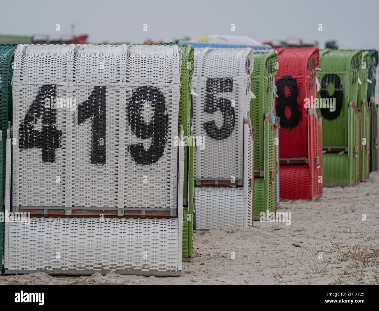 Sedie da spiaggia numerate in bianco, verde e rosso sulla spiaggia del Mare del Nord, Neuharlingersiel, Essen, Wittmund, bassa Sassonia, Germania Foto Stock