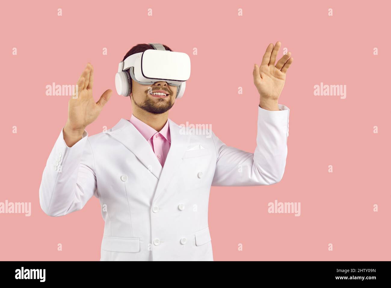 Happy man indossa un visore VR futuristico, sperimentando la realtà virtuale e sorridendo Foto Stock