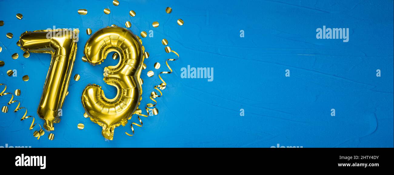 palloncino giallo dorato su fondo di cemento blu numero settantatre. Tessera di compleanno o anniversario con iscrizione 73. Celebrazione dell'anniversario Foto Stock