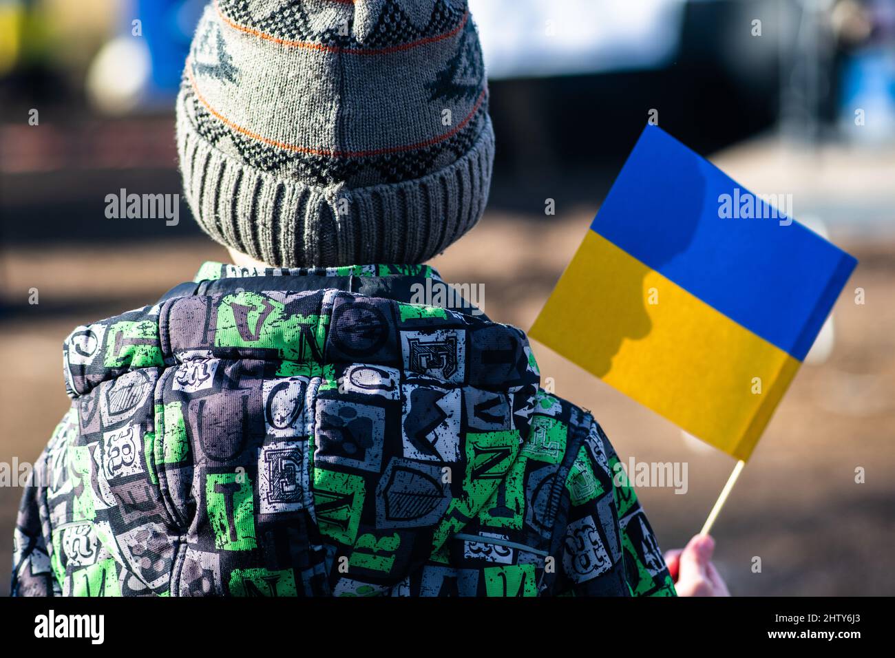 Bambino o capretto con abiti invernali, cappello e bandiera Ucraina, profilo del bambino è sulla bandiera. Guerra in Ucraina, causata da Putin e dalla Russia Foto Stock