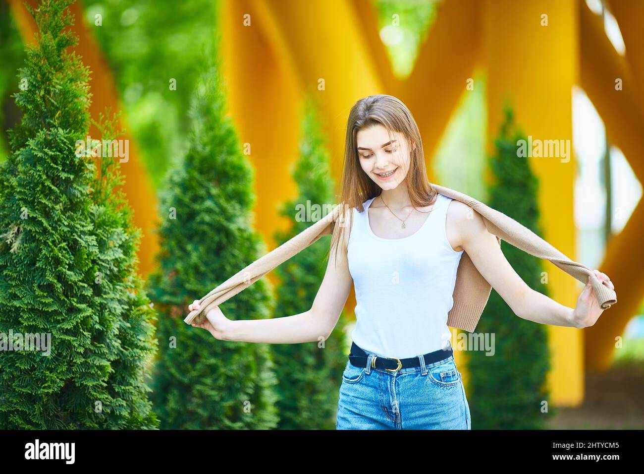 giovane adolescente che cammina lungo la strada in jeans e un maglione in una giornata estiva. Il concetto di moda giovanile. Stile di vita urbano. Foto Stock