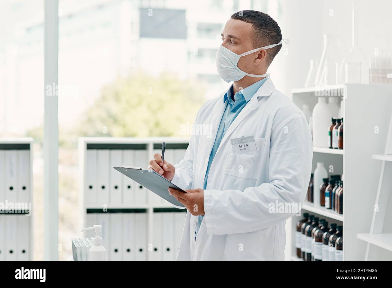 La cura per la paura è la conoscenza. Scatto di un giovane scienziato che scrive note su una clipboard in un laboratorio. Foto Stock