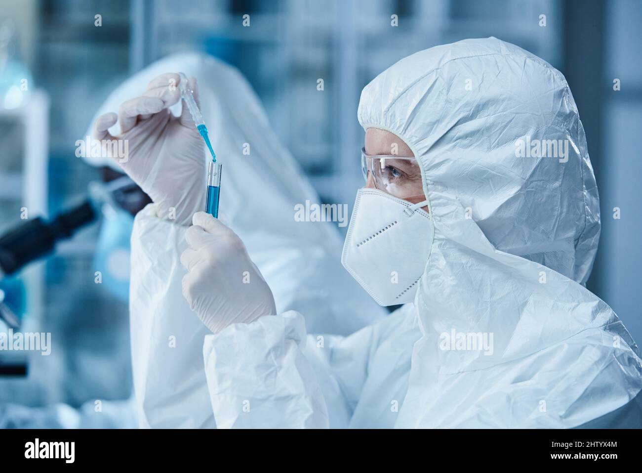 Lavoratore di laboratorio femminile in abbigliamento protettivo che lavora con campioni in provetta in laboratorio Foto Stock