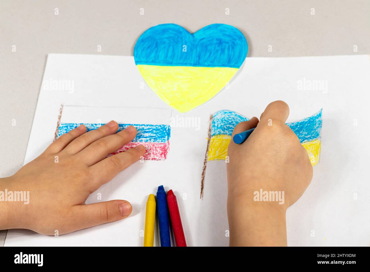 Le mani dei bambini di un bambino tirano le bandiere di primo piano di Ucraina e Russia. Vista dall'alto. Bambini contro la guerra. I bambini disegnano per la pace dentro Foto Stock