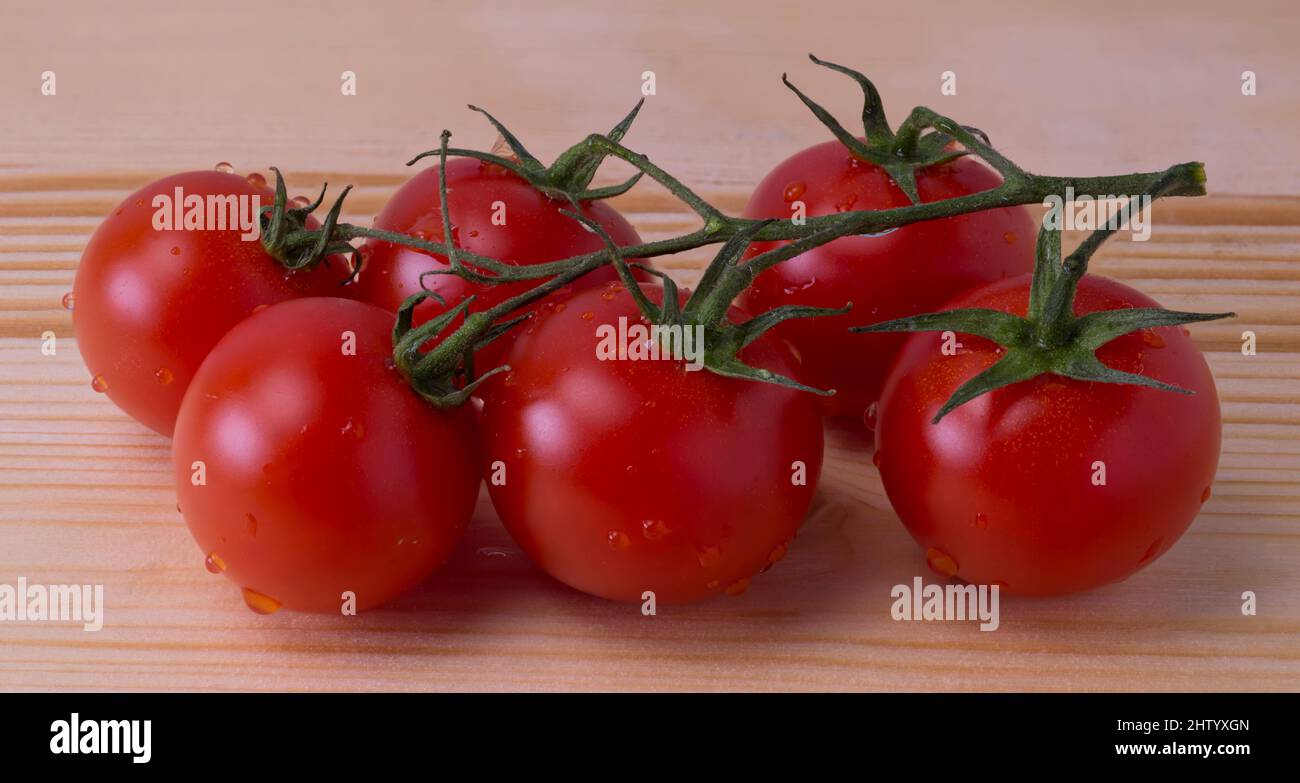 Mazzo di pomodori rossi con piccole gocce d'acqua, su tavola di legno chiaro Foto Stock