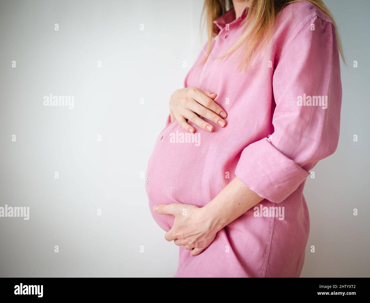 una donna incinta si alza con le mani sullo stomaco, il concetto di aspettare un bambino Foto Stock
