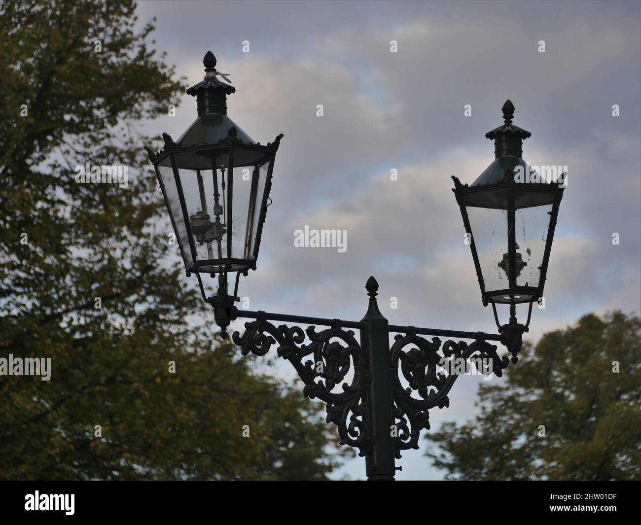 Vecchie lanterne a gas in Kaiserswerth Germania ben mantenute e ancora utilizzate, un cielo nuvoloso, e alberi Foto Stock