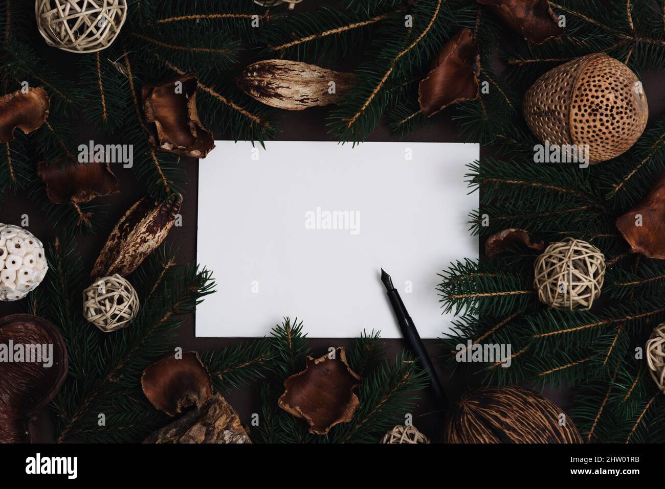 Lista dei desideri di Natale con cornice di abete e decorazione naturale di natale su sfondo scuro. Carta vuota e penna con decorazioni in Potpourri vacanza e abete Foto Stock