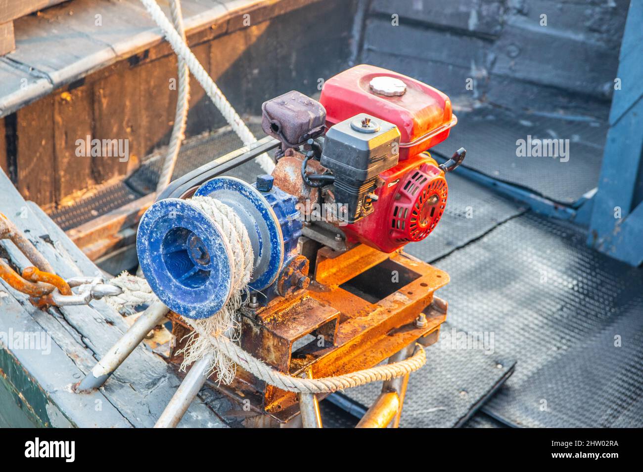 Un motore diesel con una corda per sollevare e abbassare l'ancora di una nave sul ponte di una barca da pesca Foto Stock