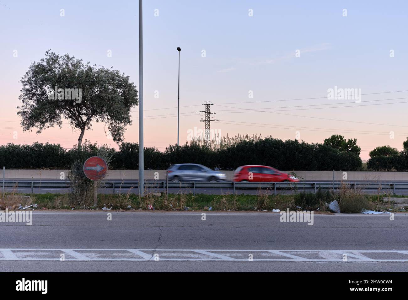 Strada con un vecchio cartello stradale e le auto sono passare vicino durante il tramonto Foto Stock