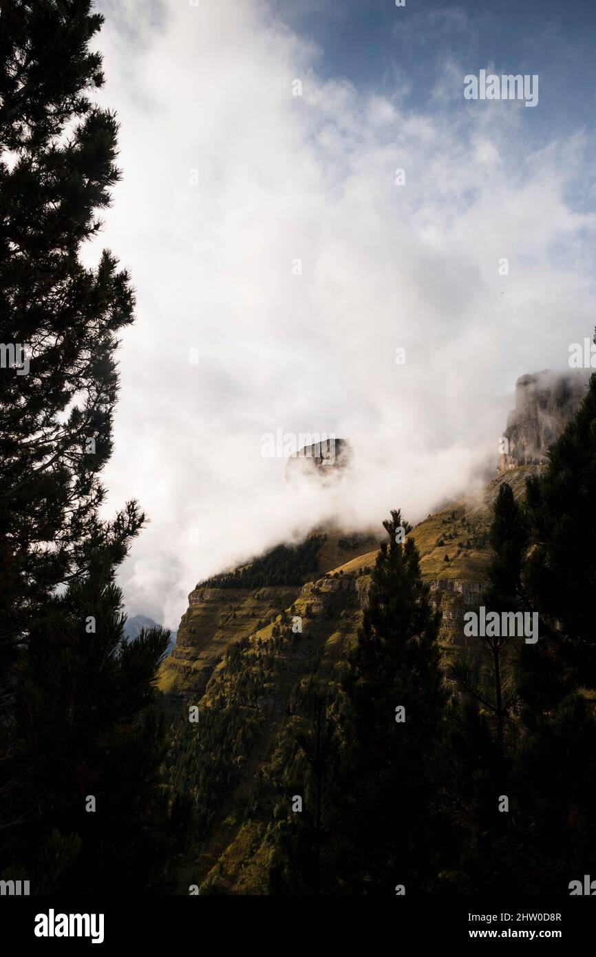 Pendii di montagna tagliati in verticale coperti di erba verde e vegetazione sotto le nubi nubi nebbie Foto Stock