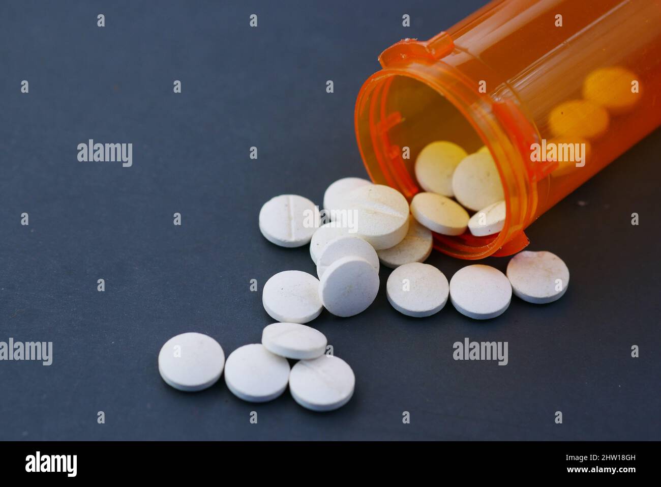 pillole mediche di colore bianco che si spillano su sfondo nero Foto Stock
