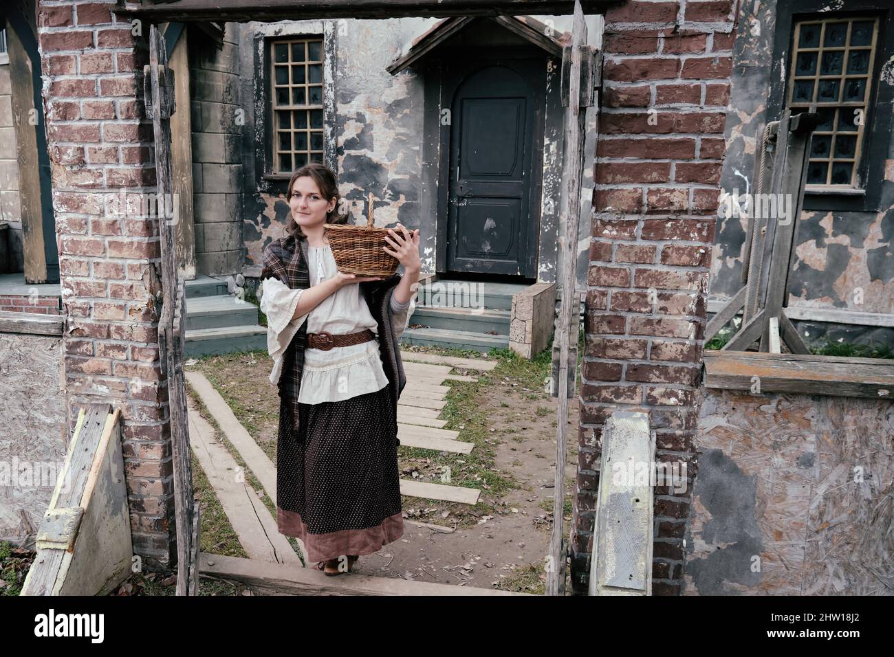 Donna a tutta lunghezza al vecchio cancello di legno con un cestino nelle sue mani. Abiti vintage in stile Halloween 18-19th secolo Foto Stock