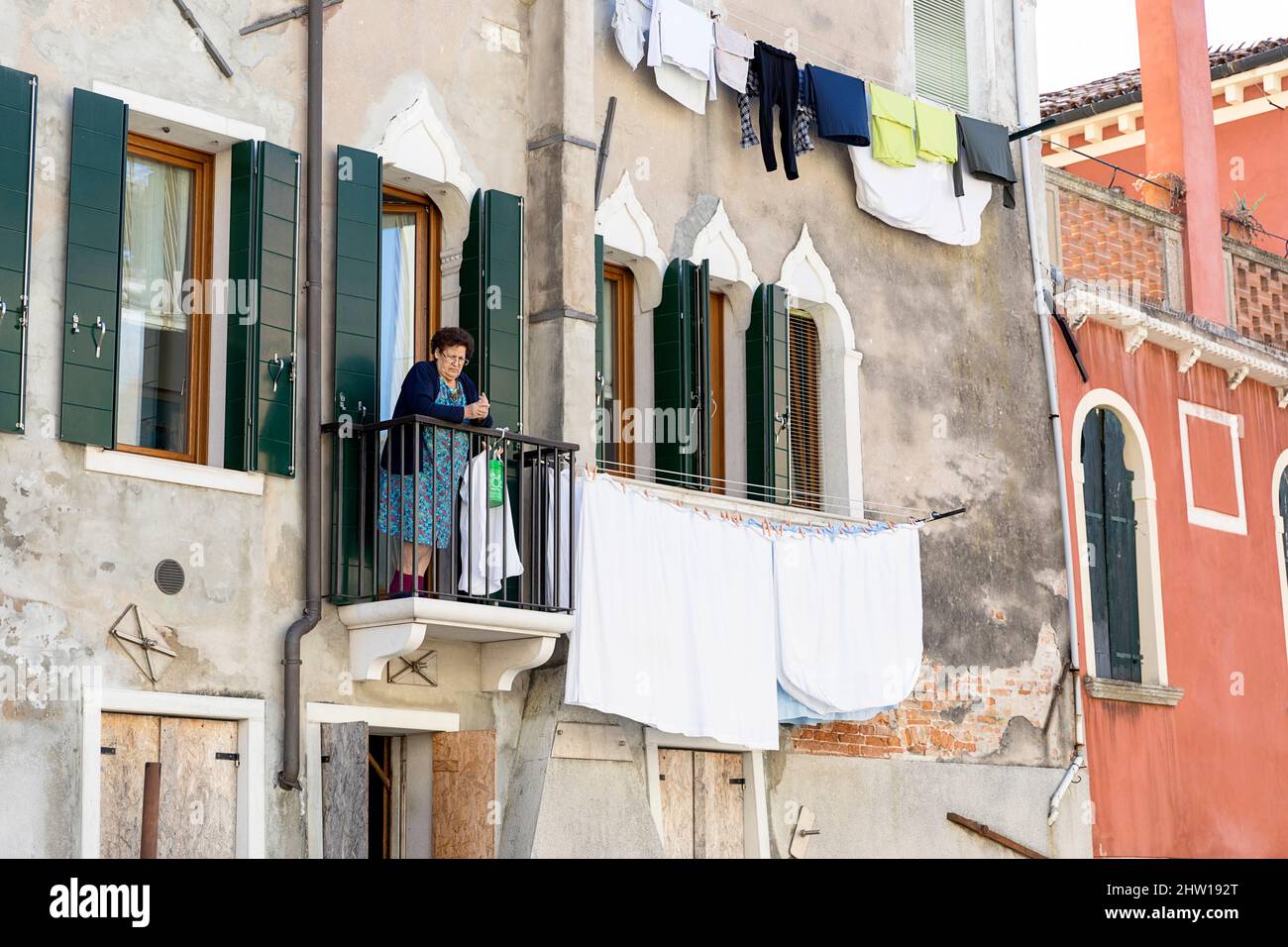 Donna del posto sul balcone di un'antica casa medievale sul canale dell'acqua di Venezia, lavanderia sul balcone, Italia Foto Stock