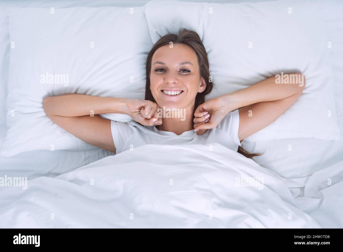 Buongiorno. Vista dall'alto della bella giovane donna che si svegliava felice nel letto e guardando nella fotocamera Foto Stock