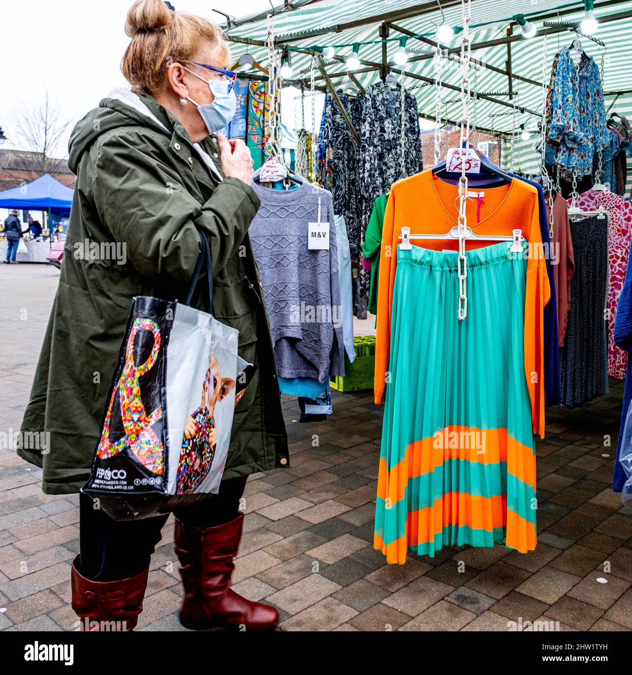 Epsom Surrey London UK, Marzo 03 2022, Donna in piedi da sola Browsing Fashion Clothing Market Stall indossando Protactive Covid-19 maschera facciale Foto Stock