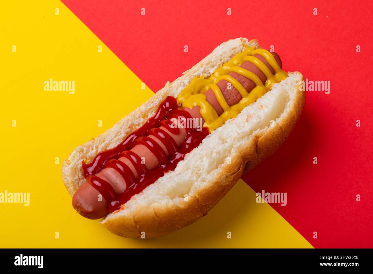 Primo piano di hot dog con salsa di pomodoro e mostered su sfondo a due toni con spazio copia Foto Stock