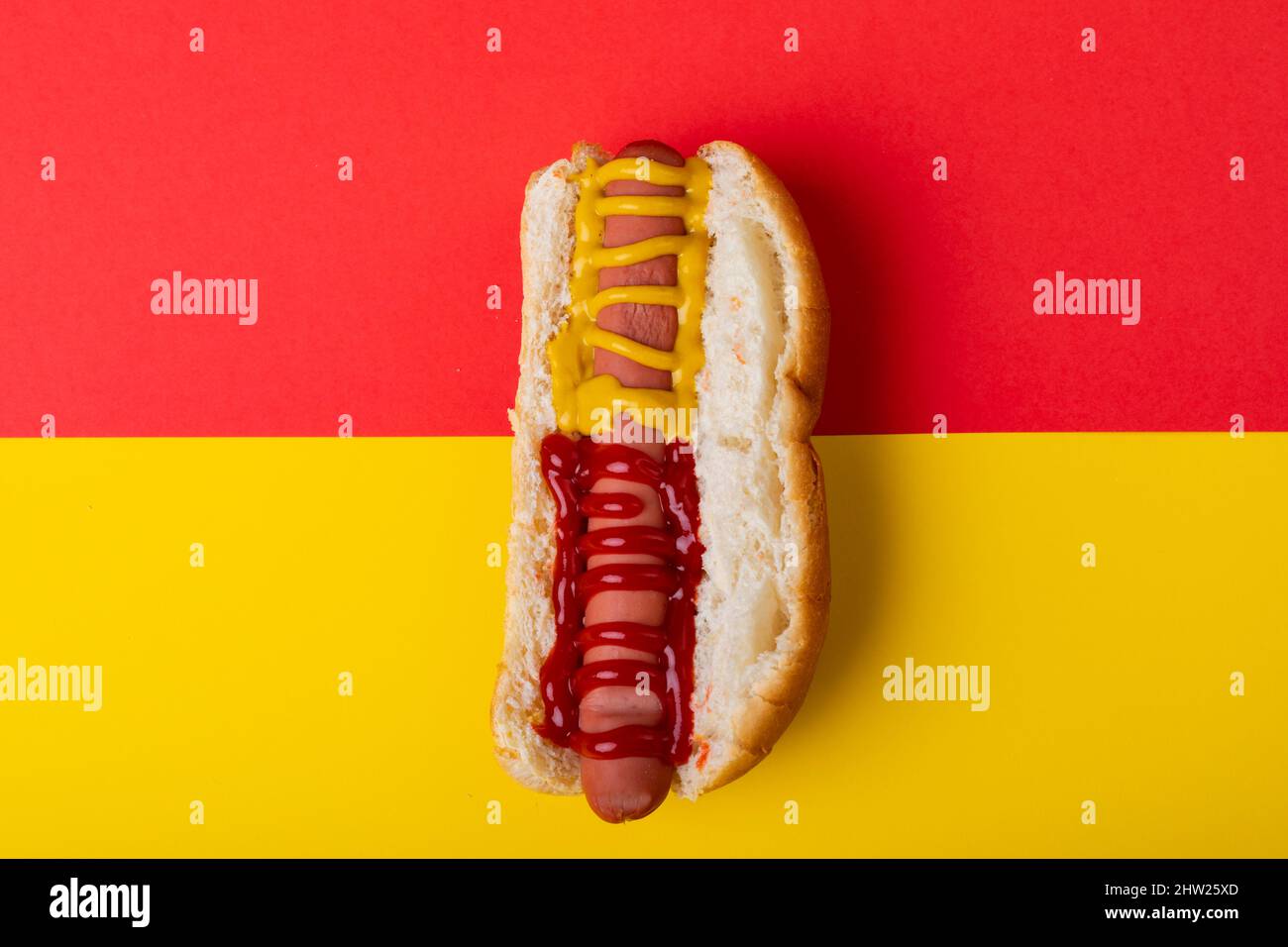 Primo piano di hot dog con salsa di pomodoro e mostered su sfondo a due toni con spazio copia Foto Stock