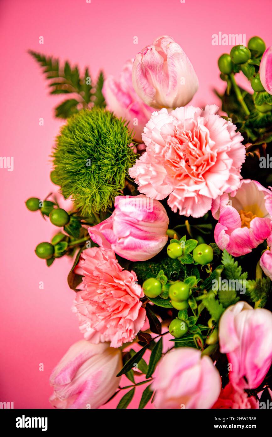 Bel bouquet di fiori rosa e verde in primo piano su uno sfondo rosa Foto Stock