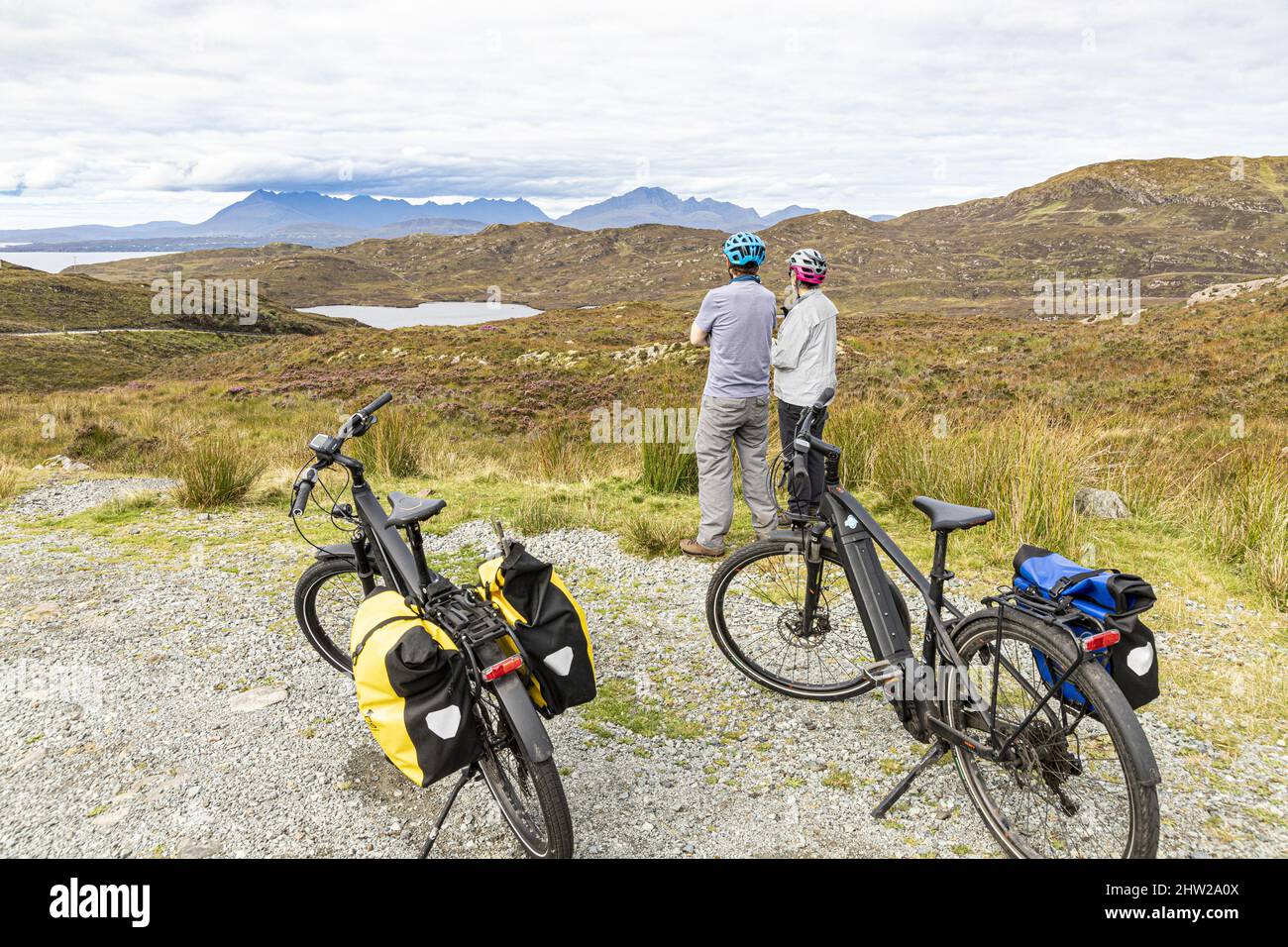 Due ciclisti in bici elettriche che guardano a nord su Loch Dhughill sulla penisola di Sleat nel sud dell'isola di Skye, Highland, Scozia Regno Unito Foto Stock