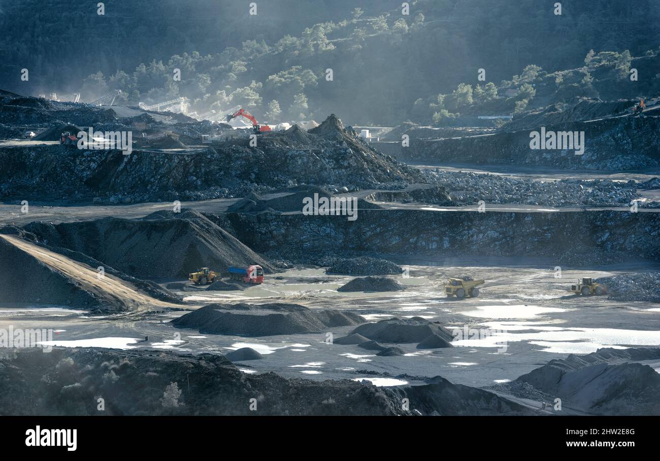 Cave con escavatori, pale caricatrici e dumper da miniera e mucchi di pietra frantumata, paesaggio industriale Foto Stock