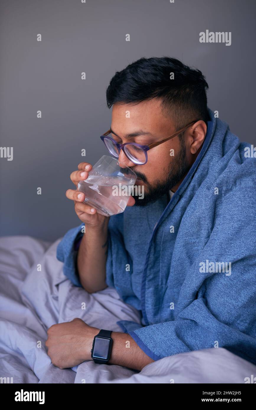 Un uomo adulto beve un effervescente per trattare l'influenza Foto Stock