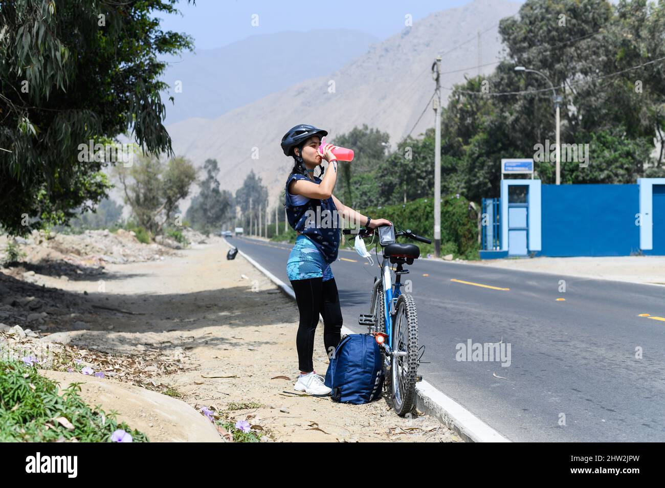 la donna beve acqua vicino a una bicicletta dopo lo sport Foto Stock