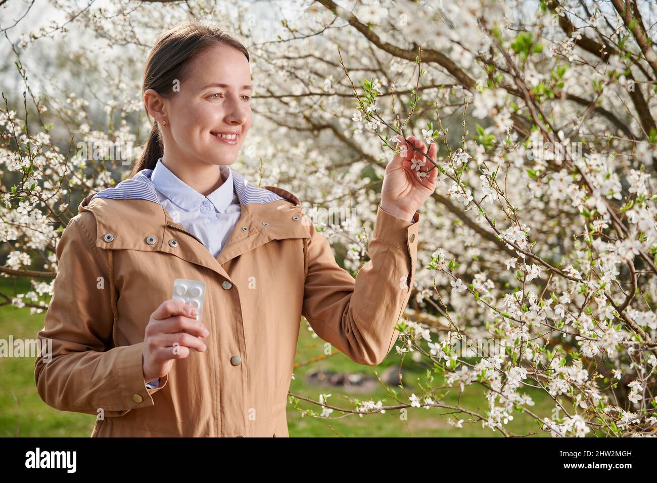 Donna allergica che soffre di allergia stagionale in primavera, posando in  giardino fiorito in primavera. Giovane donna che usa allergia droga tra  alberi in fiore. Concetto di farmaco antistaminico Foto stock -