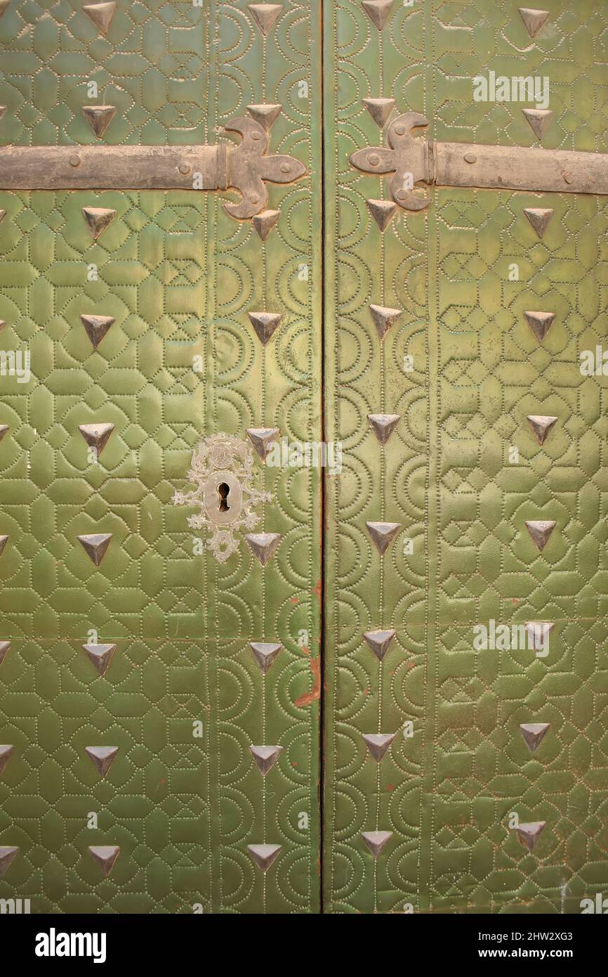 Primo piano della parte esterna di una storica porta in metallo con rivetti in un colore verde lucido, città vecchia, Alicante, Spagna. Foto Stock