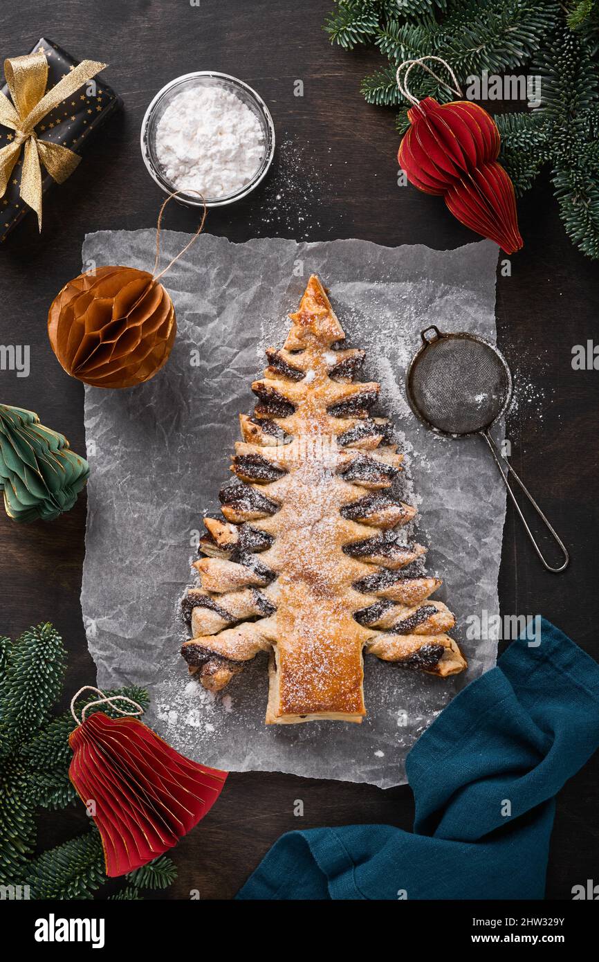 Pasta sfoglia albero di Natale con pasta di cioccolato, cosparso di zucchero in polvere su vecchio sfondo di legno scuro. Dolci natalizi o natalizi. Vista dall'alto. Co Foto Stock